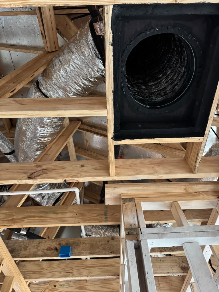 Insulated flexible duct connected to a ceiling opening between exposed wood framing