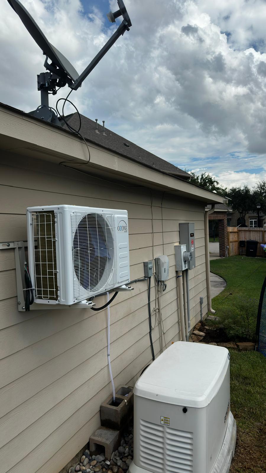 White outdoor mini-split mounted on brackets on a home with beige siding